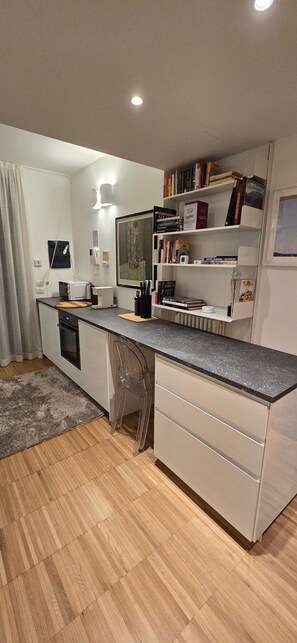 Una cocina moderna con una isla central, electrodomésticos integrados y una estantería.