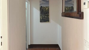 Ein Flur mit gefliestem Boden, Holzboden und einem an der Wand befestigten Spiegel.
