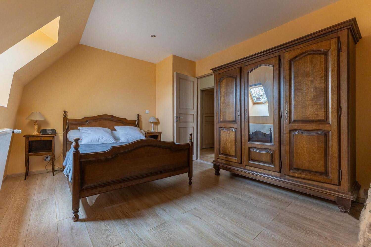 Een slaapkamer met een houten bed, een kledingkast en een dakvenster.