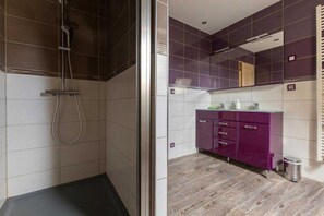 Une salle de bain avec une douche, un lavabo et un meuble-lavabo avec des tiroirs.