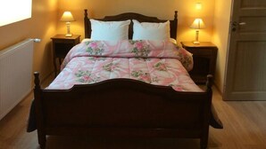 A bedroom with a wooden bed, floral bedding, two bedside lamps, and a door.