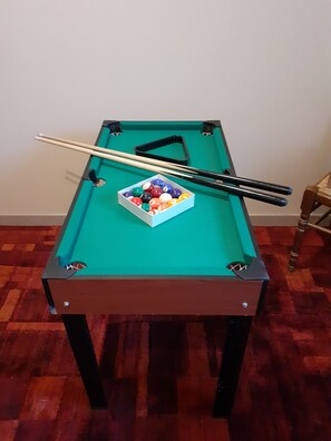 A pool table with a set of pool balls, a cue stick, and a pair of pool cues.