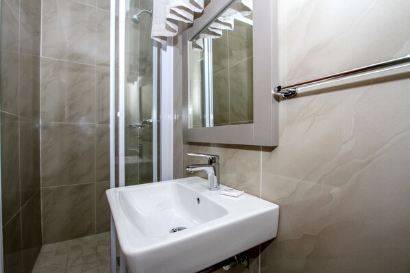 A bathroom with a white sink, a mirror, and a glass shower enclosure.