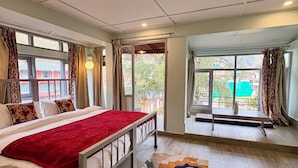 A bedroom with a bed, a bench, and a view of the outside. - Evolve Dharamkot  (Dharamshala)