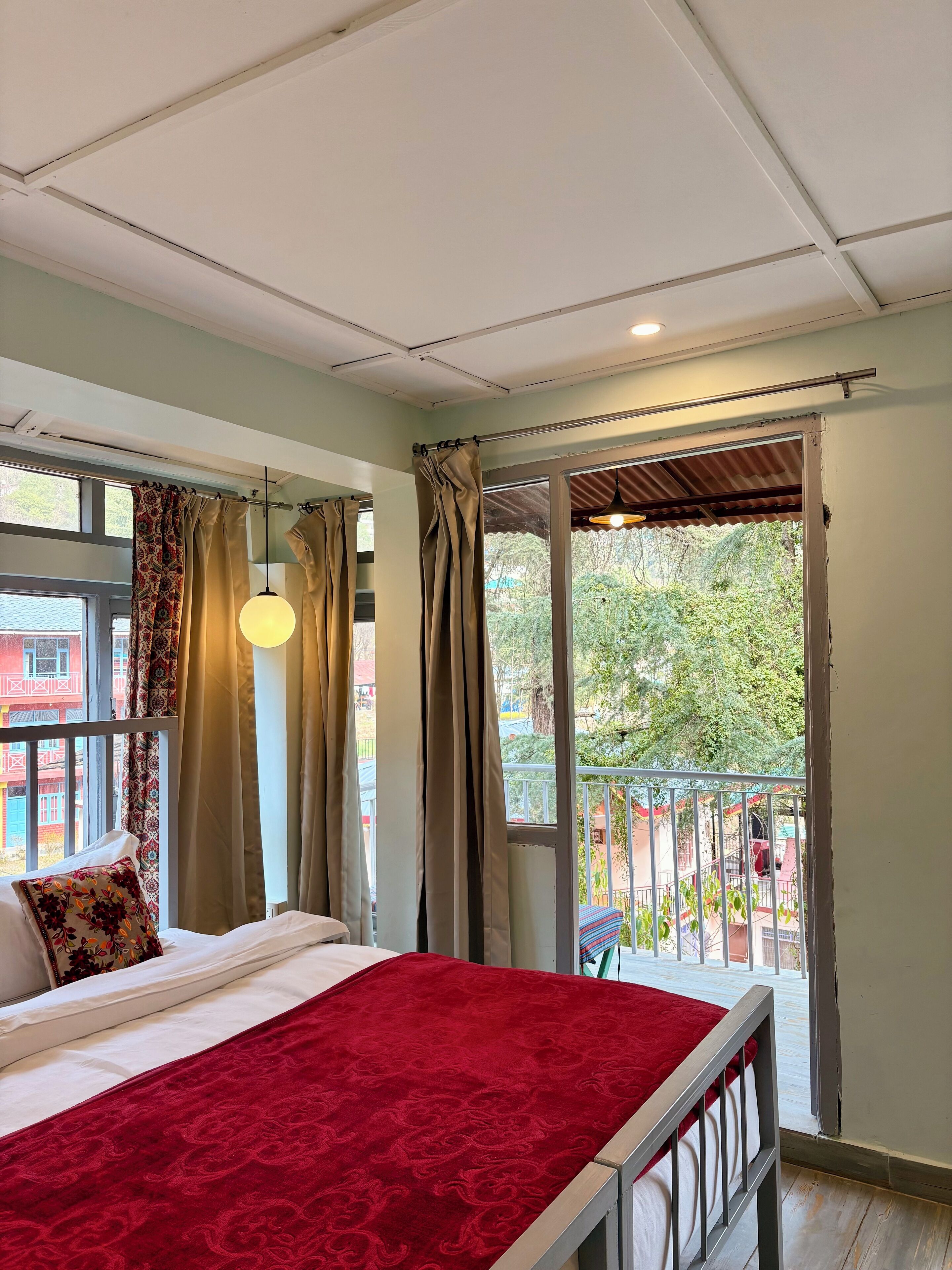 A bedroom with a bed, curtains, and a balcony with a railing.