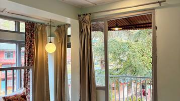 Ein Schlafzimmer mit Bett, Vorhängen und einem Balkon mit Geländer.