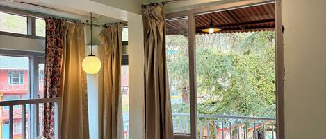 A bedroom with a bed, curtains, and a balcony with a railing.