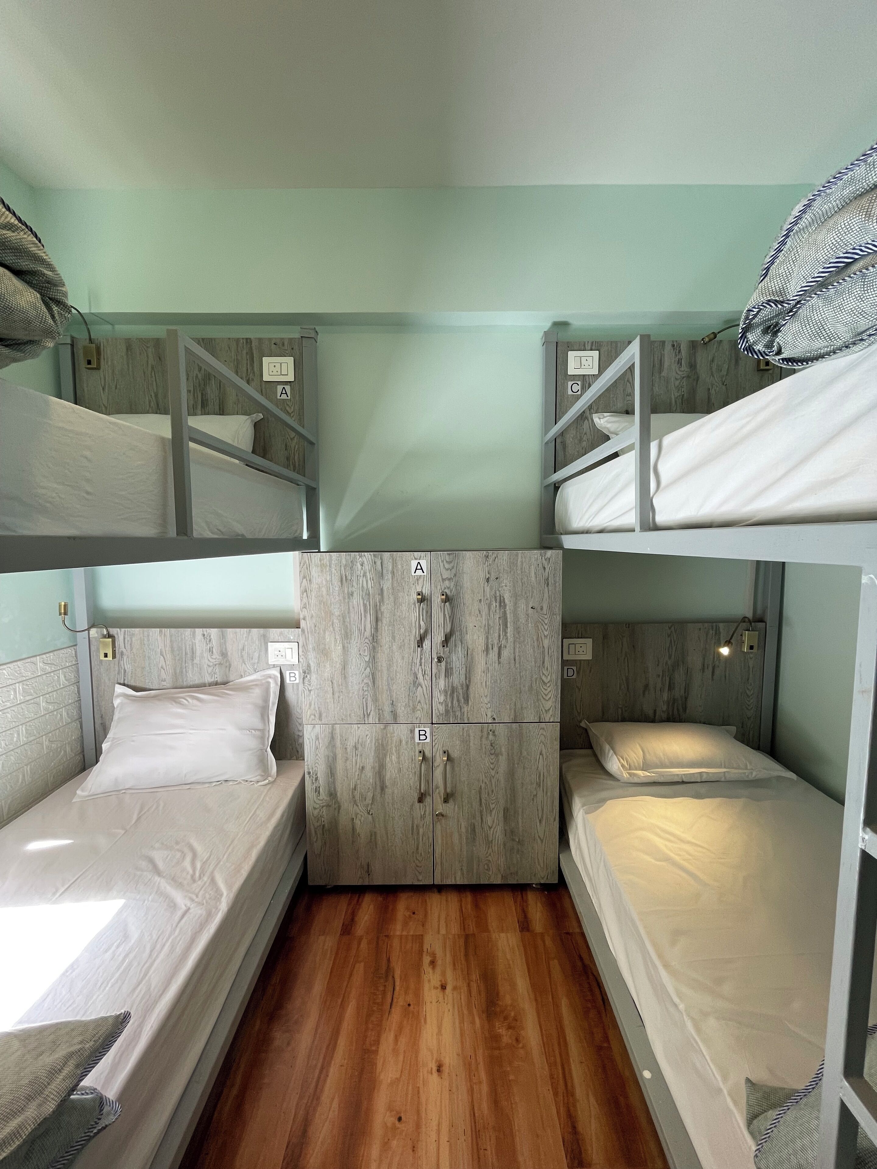 A compact room with bunk beds, a wardrobe with multiple compartments, and a wooden floor.