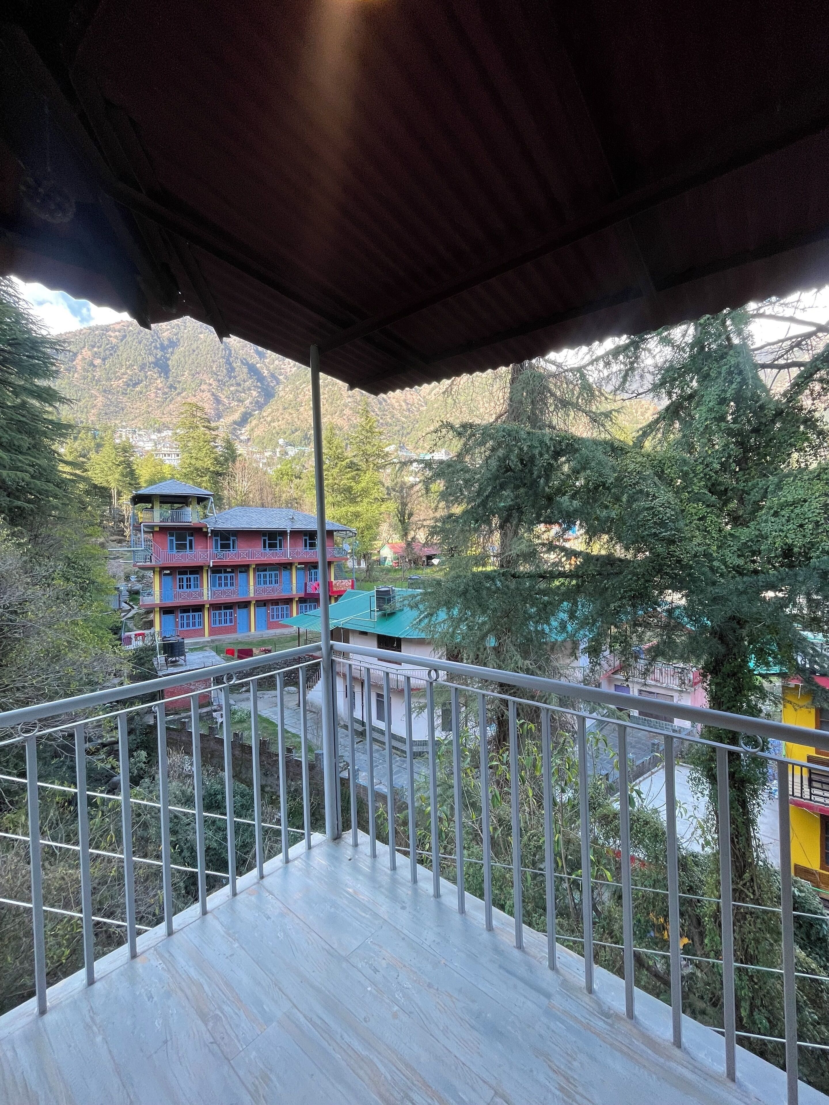 A balcony with a metal railing overlooking a mountainous area with colorful buildings.