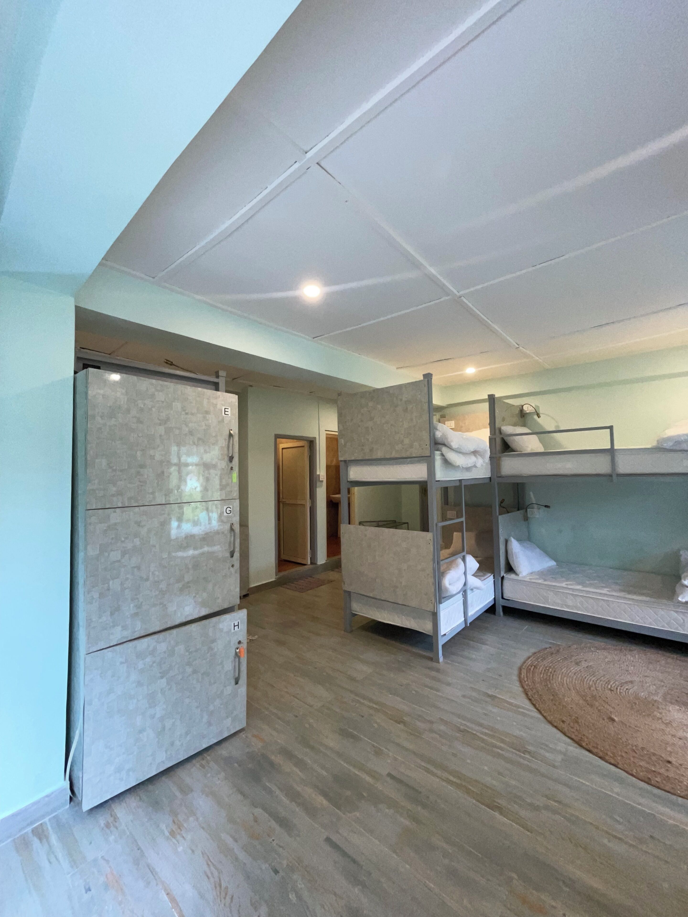 A room with bunk beds, a refrigerator, and a door leading to another room.
