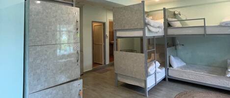 Una habitación con literas, un refrigerador y una puerta que da a otra habitación.