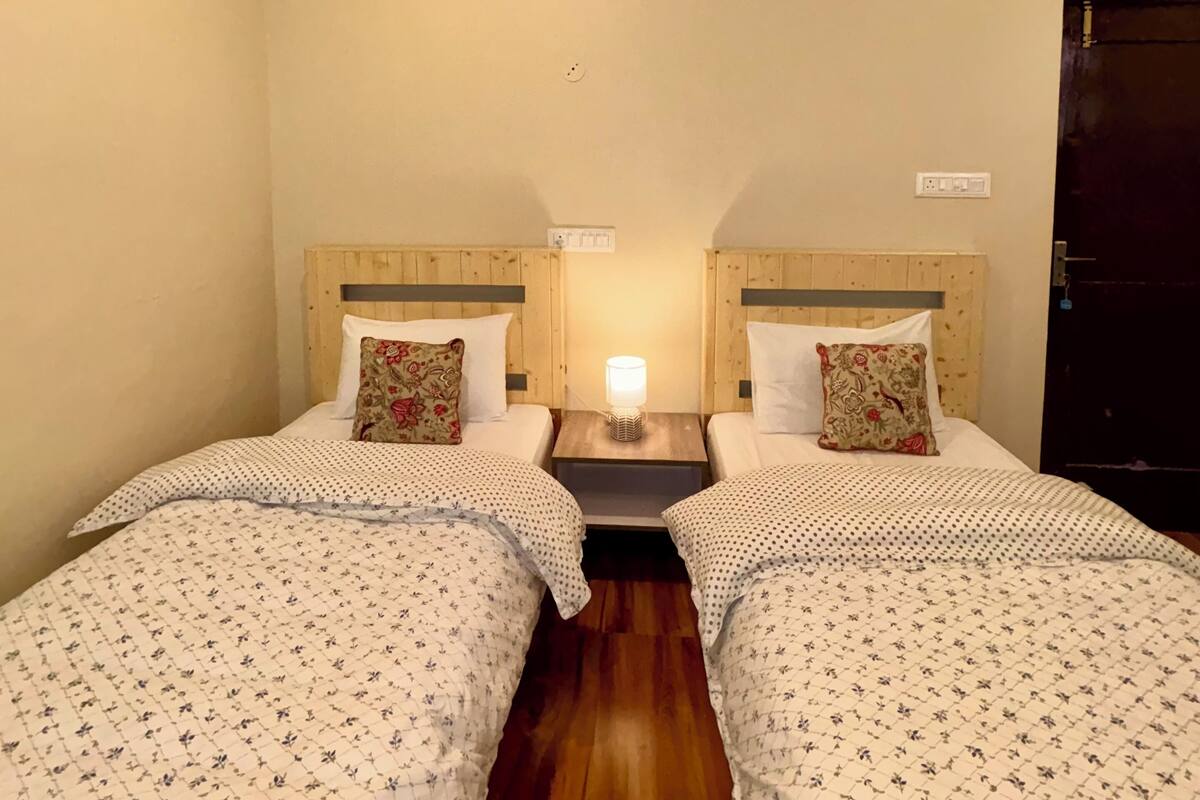 Ein Hotelzimmer mit zwei Betten, Holz-Kopfteilen, einem Nachttisch mit Lampe und einer Tür.
