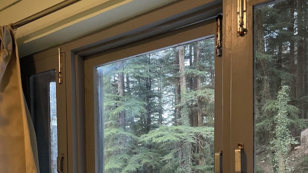 A room with a large window overlooking a forested area. - Evolve Dharamkot  (Dharamshala)