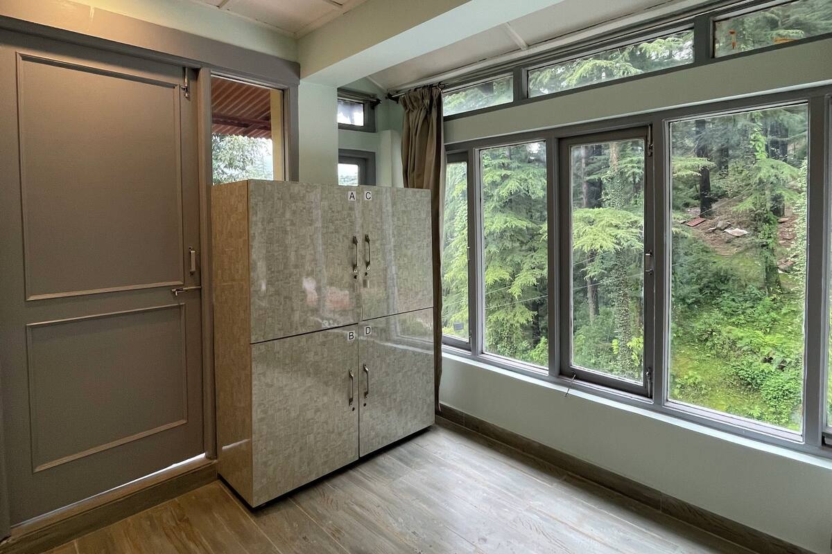 Ein Zimmer mit großem Fenster, Holzboden und einer Kommode mit Schubladen.