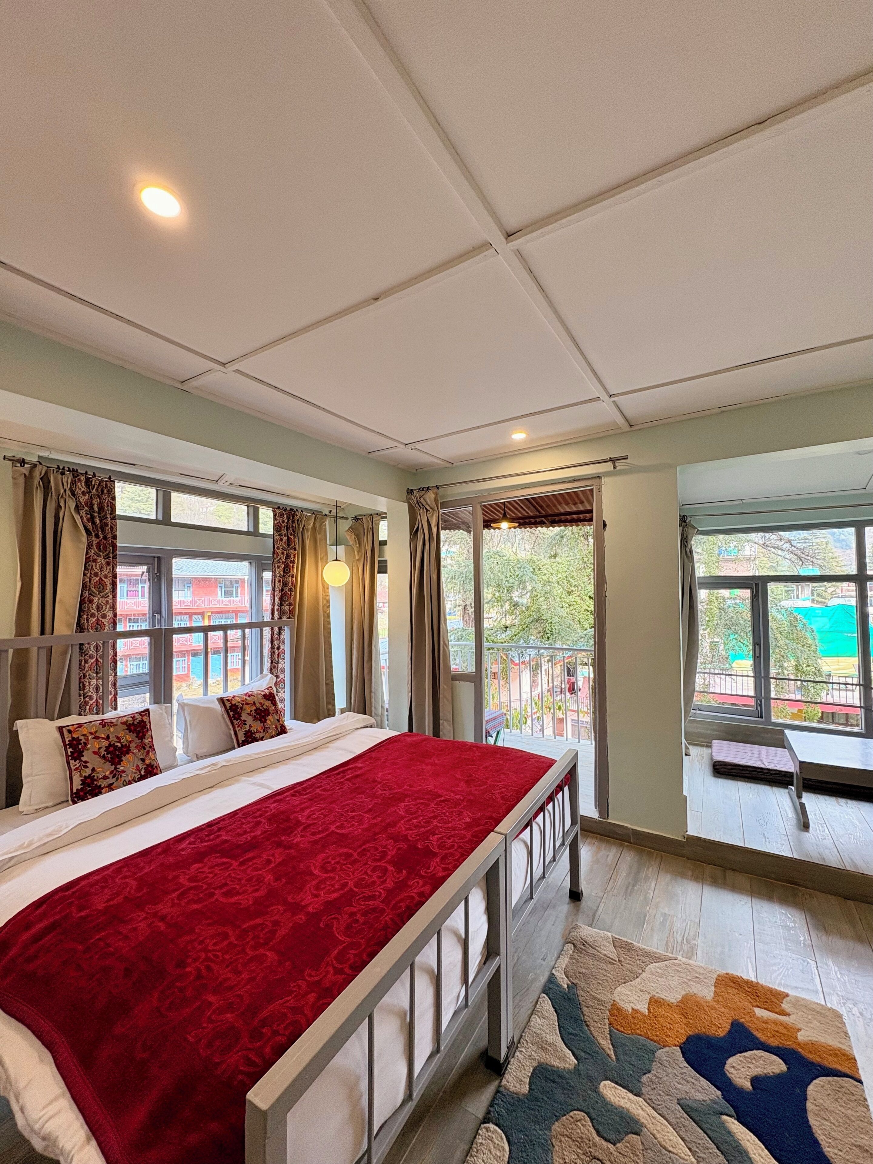 A hotel room with a bed, a balcony, and large windows.
