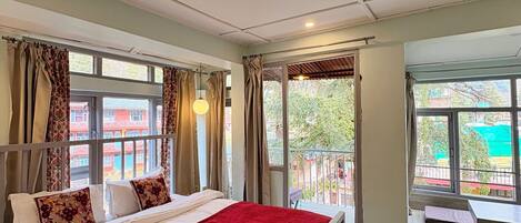 A hotel room with a bed, a balcony, and large windows.