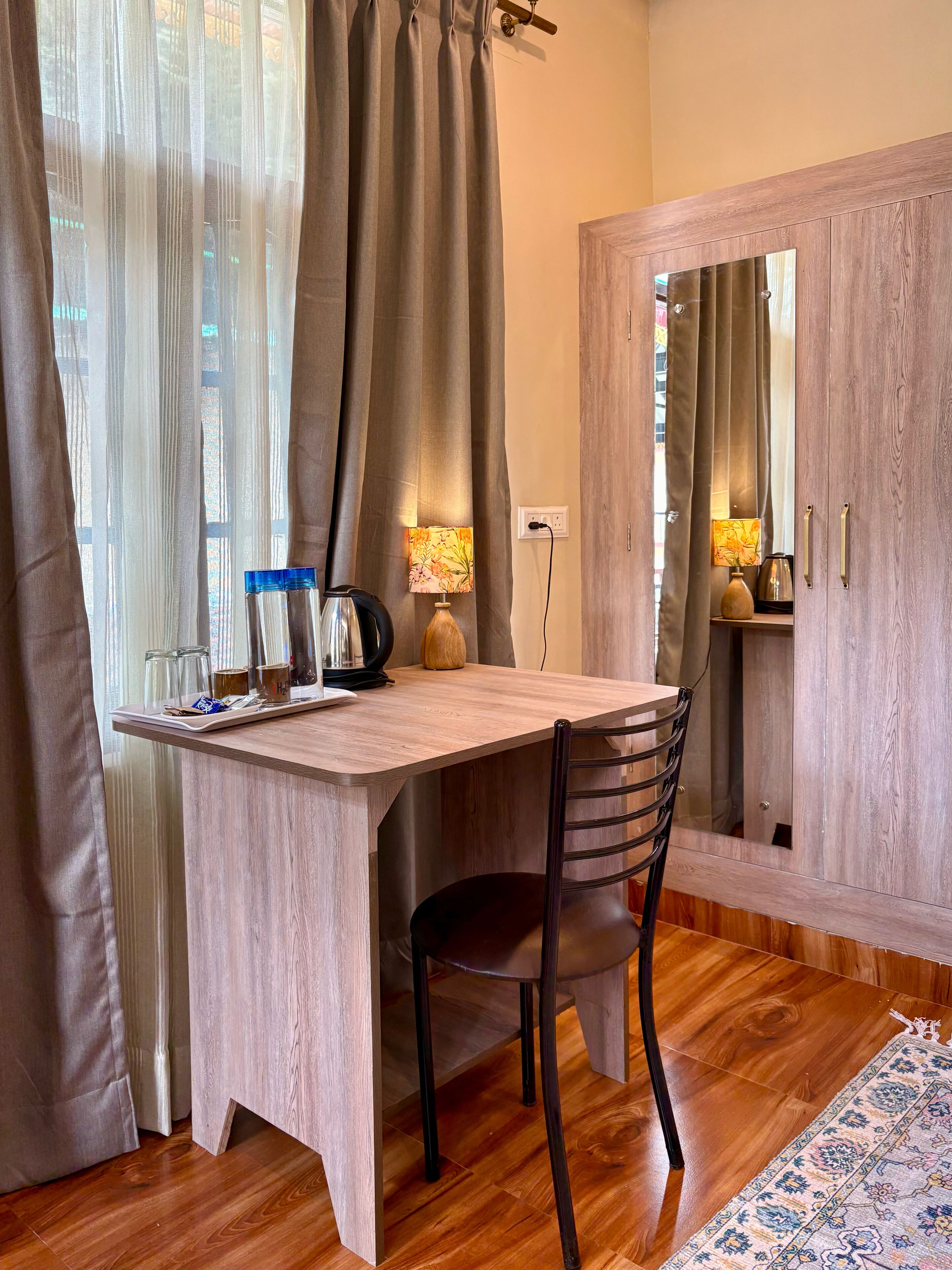 A wooden desk with a chair, a lamp, and a coffee maker.