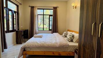 A bedroom with a bed, a wardrobe, a desk, and a window with curtains.