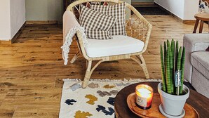 A cozy living room with a wicker chair, a small table with a candle, and a patterned rug. - Nasza Chata- hottub, fireplace, kids-friendly, grill, workspace, free parking (Kacwin)