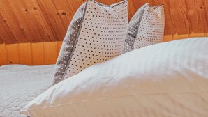 A neatly made bed with white bedding and two pillows, one with a polka dot pattern. There are three candles on a bedside table. - Nasza Chata- hottub, fireplace, kids-friendly, grill, workspace, free parking (Kacwin)