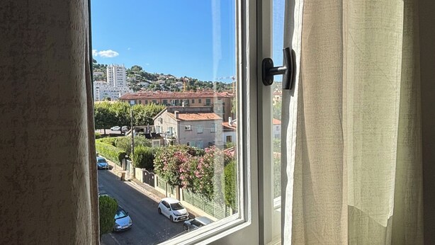 A window with a view of a street and buildings. - La Cachette du Sud  (Vallauris)
