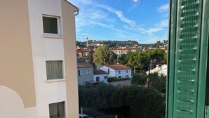A view from a balcony overlooking a street with parked cars and buildings in the background. - La Cachette du Sud  (Vallauris)