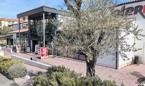 A building with a glass facade, a tree in front, and a sign with '10' visible. - La Cachette du Sud  (Vallauris)