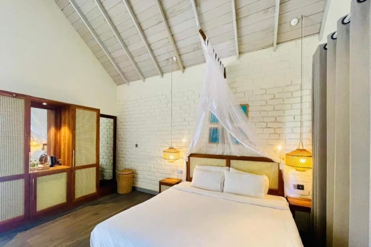Un dormitorio con cama, dosel, pared de ladrillo y suelo de madera.