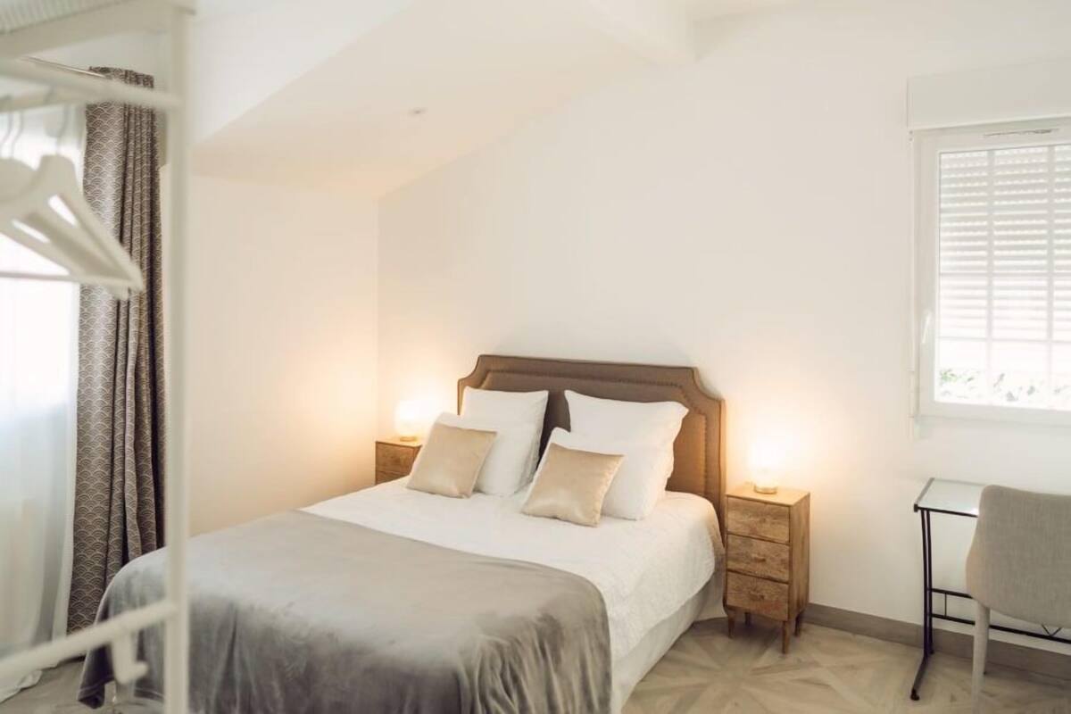 A bedroom with a bed, bedside tables, a desk, and a chair.