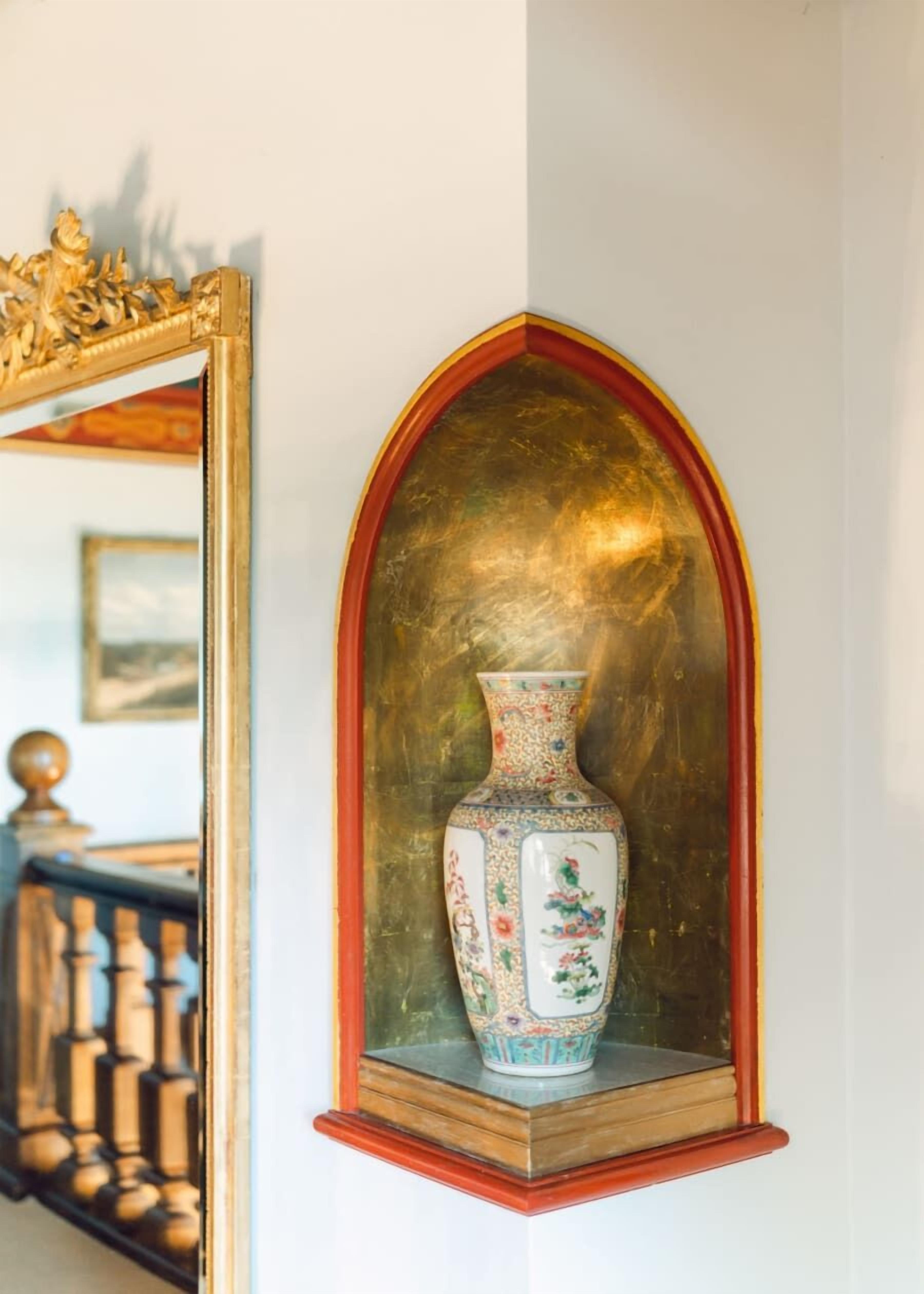 Un vase décoratif orné de motifs floraux, posé sur une étagère.