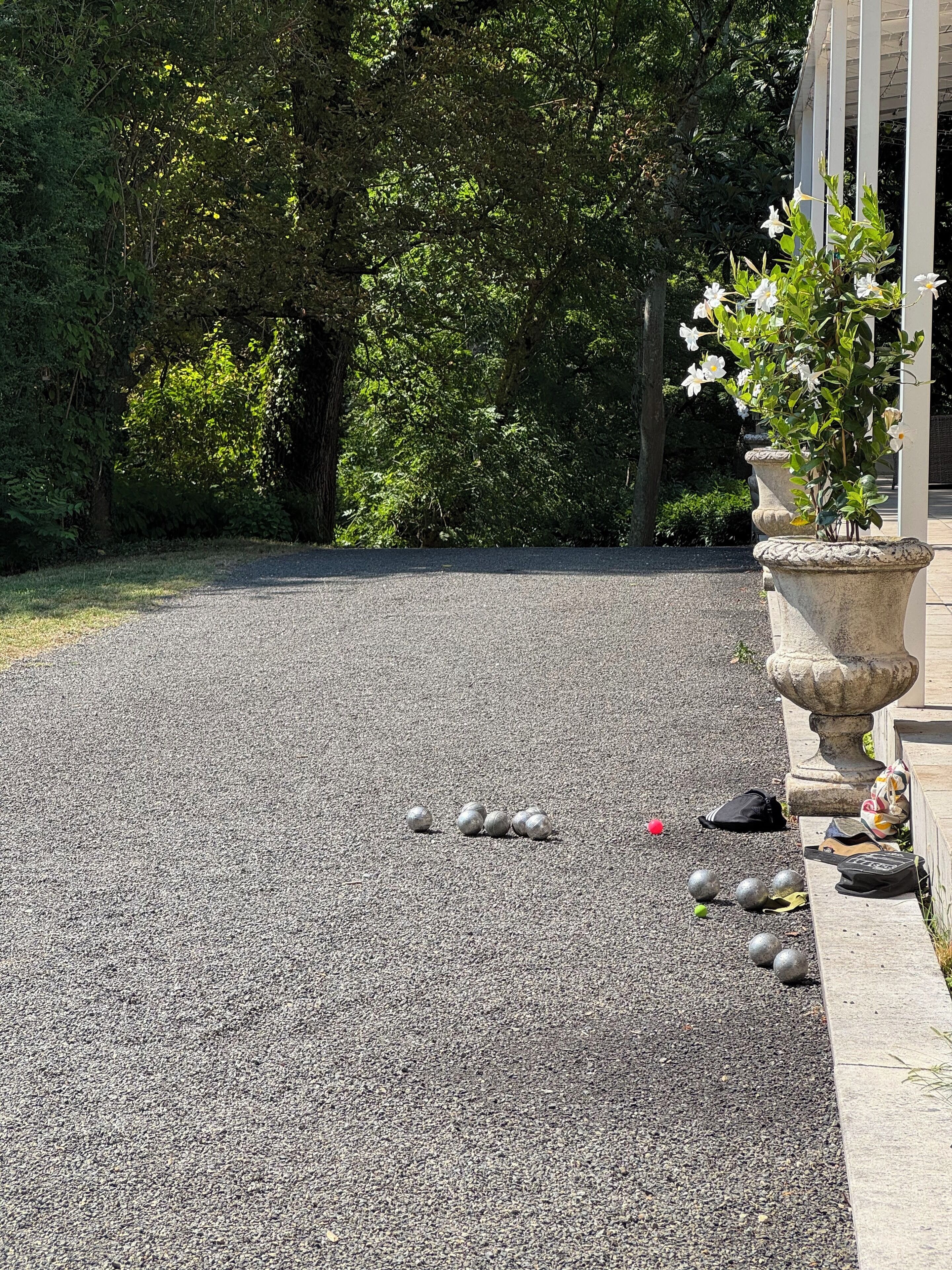 A gravel path with a row of potted plants and a stone bench.