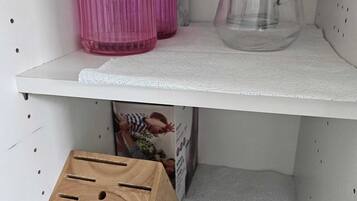 A shelf with a pink vase, a clear pitcher, and a wooden storage box.