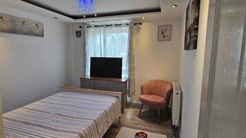 Ein Schlafzimmer mit Bett, Fernseher, Stuhl und Teppich mit einem Hütchenspiel.