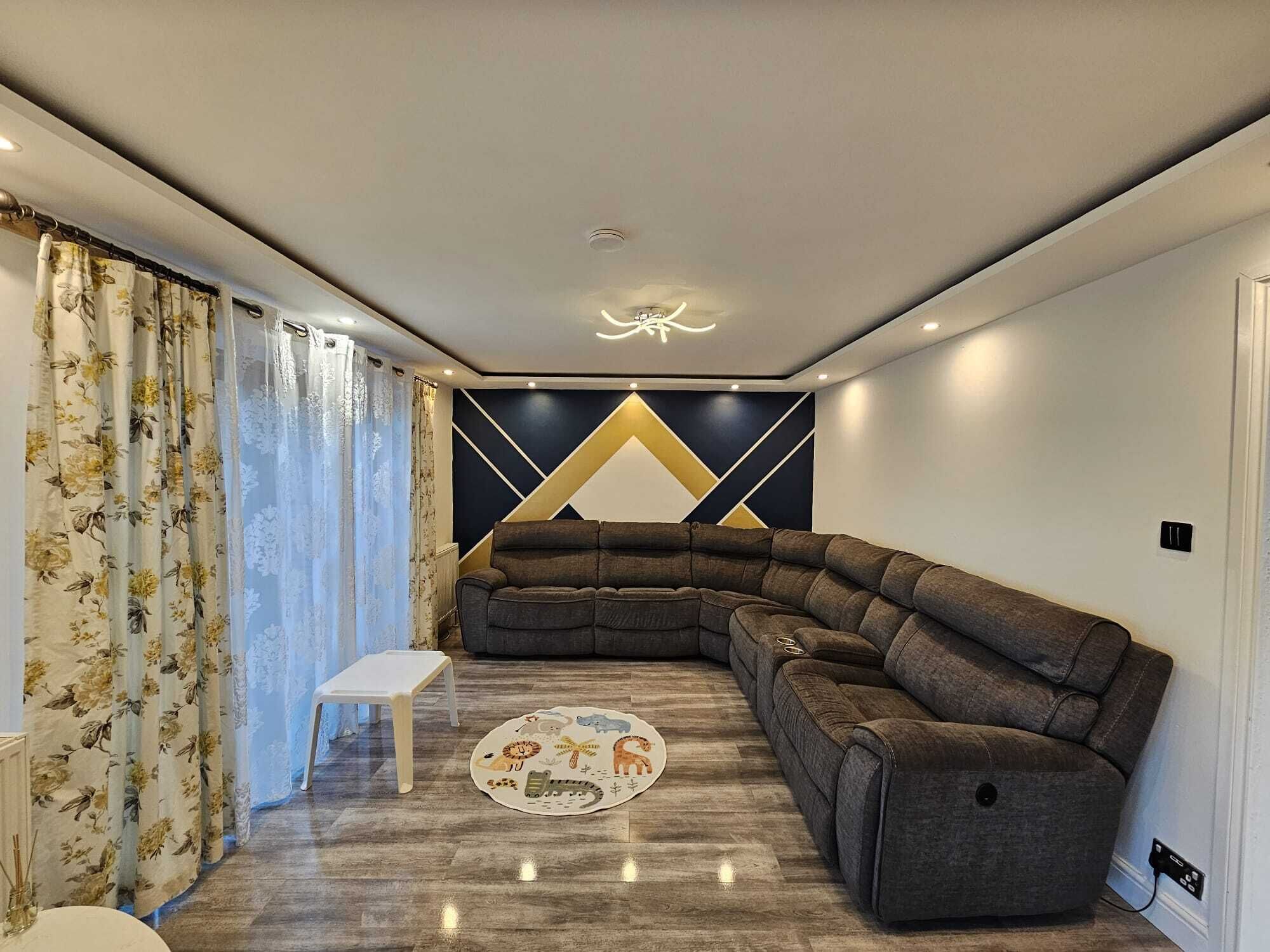 A modern living room with a sectional sofa, a small white table, and a decorative rug.