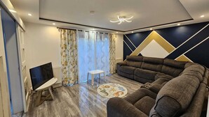 Una sala de estar moderna con un sofá seccional, un televisor de pantalla plana y un diseño decorativo en la pared.