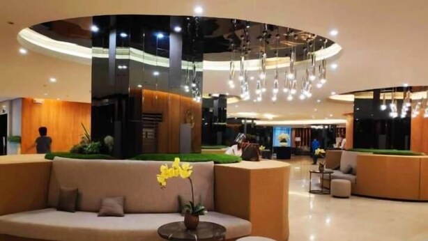 Eine moderne Lobby mit einer gebogenen Rezeption, einer Couch und einem kleinen Tisch mit einer Pflanze.