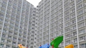 Ein Spielplatz mit Rutschen und Klettergerüsten vor einem Hochhauswohngebäude.