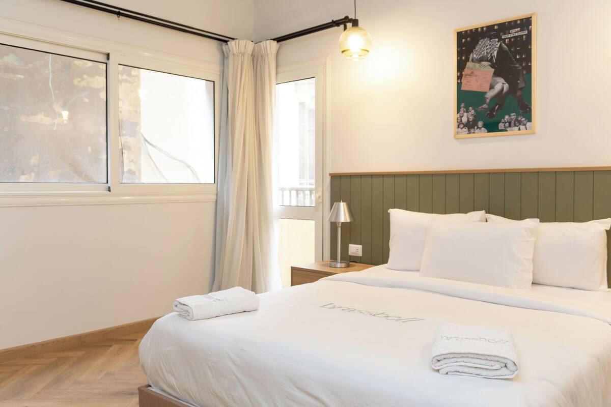 Una camera d'albergo con un letto grande, un comodino, una lampada e un quadro appeso al muro.