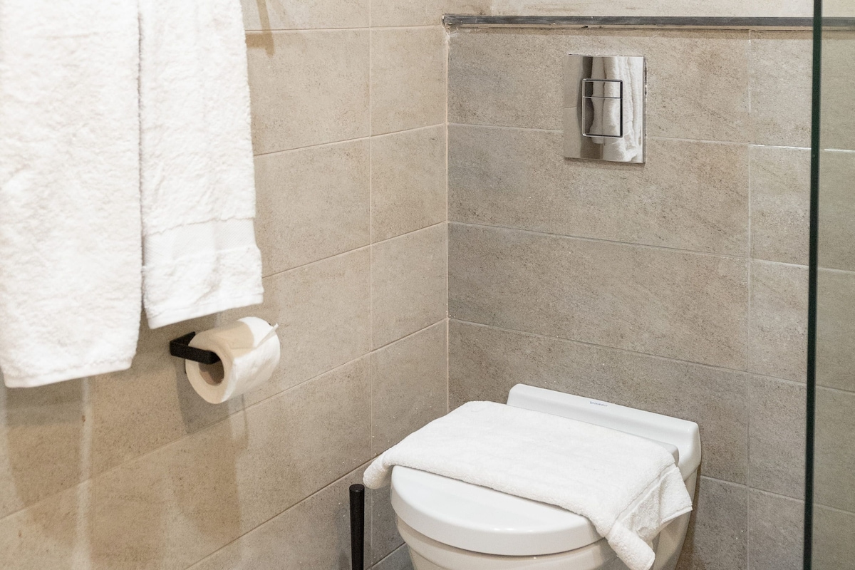 A bathroom with a toilet, a towel rack, and a toilet paper holder.