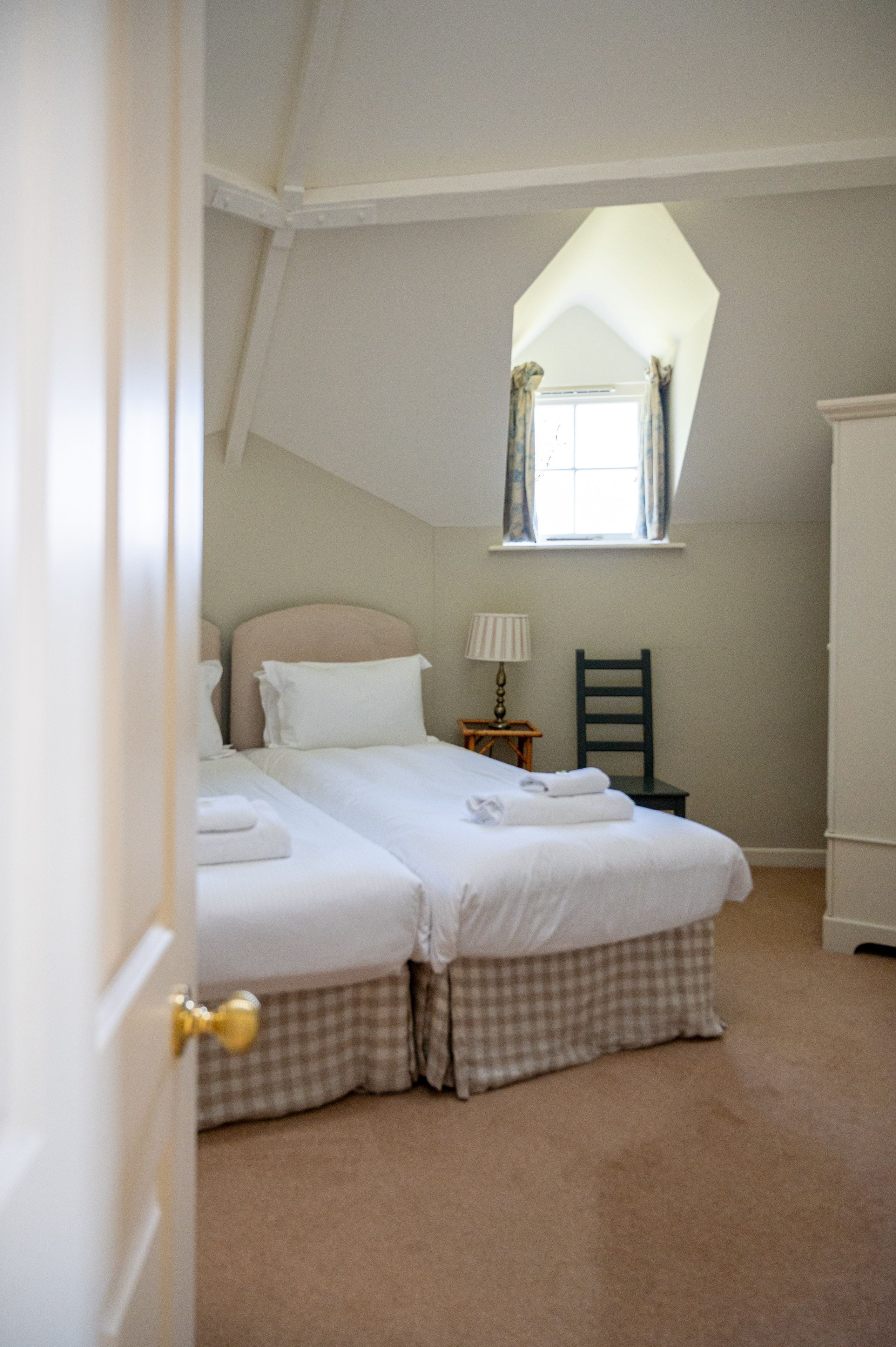 A bedroom with a bed, a chair, a nightstand, and a window.