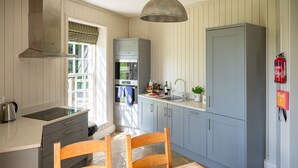 A modern kitchen with a built-in oven, a sink, and a dining area with a table and chairs.