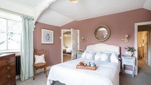 Een slaapkamer met een bed, een kaptafel, een stoel en een raam met gordijnen.