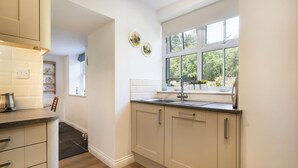 A kitchen with white cabinets, a black countertop, and a window with a view of greenery. - Cringlemire Farm Cottage -  17th century cottage that sleeps 4 guests  in 2 bedrooms (Bouth)