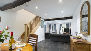 A dining area with a wooden table, chairs, and a wine bottle. There is a staircase leading to another room. - Cringlemire Farm Cottage -  17th century cottage that sleeps 4 guests  in 2 bedrooms (Bouth)