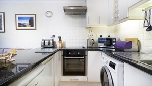 A compact kitchen with a built-in oven, microwave, and washing machine.