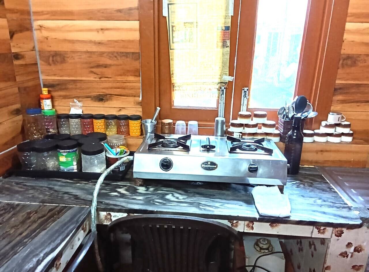 A kitchen with a gas stove, various containers, and a window.