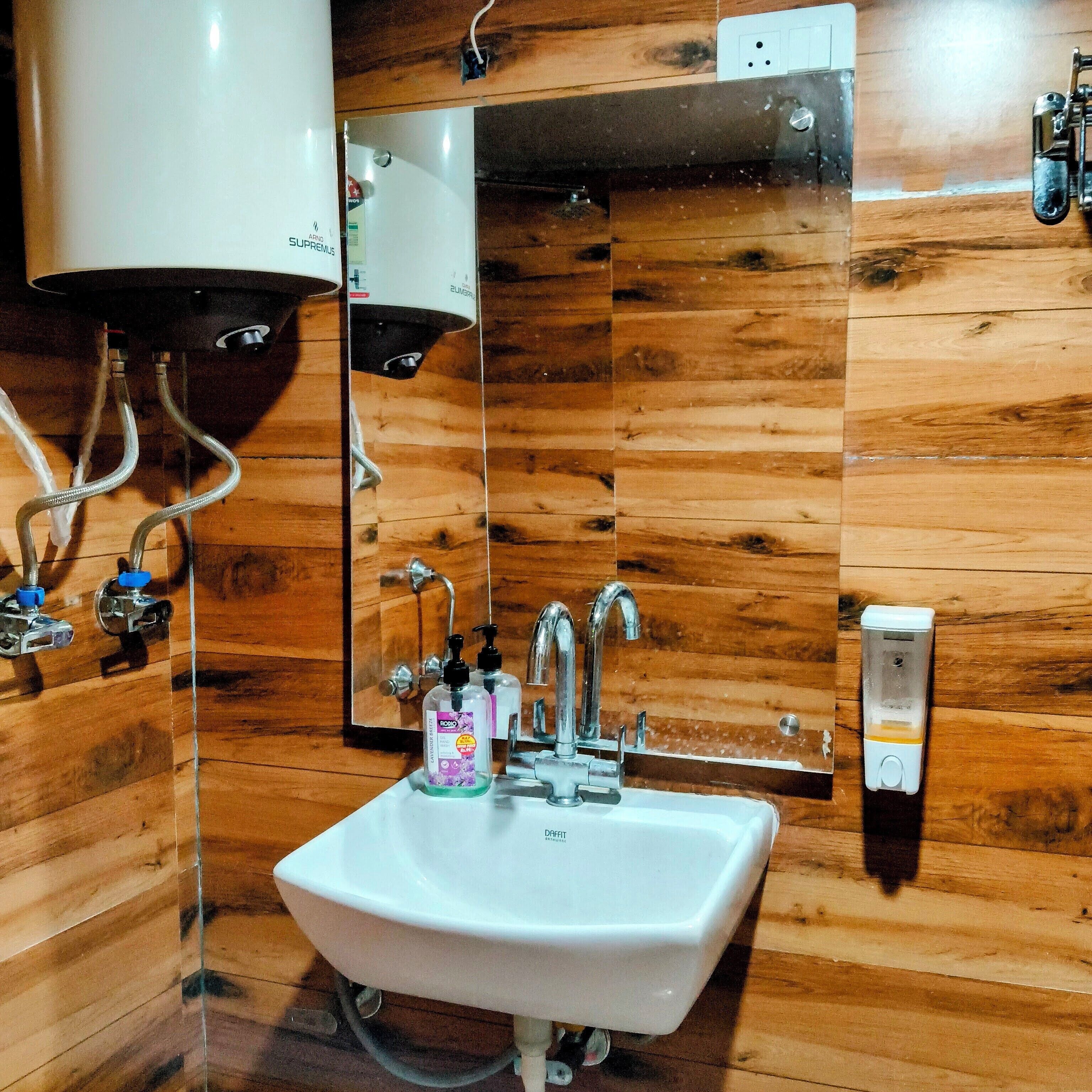 A bathroom with wooden walls, a white sink, a mirror, and a handheld showerhead.