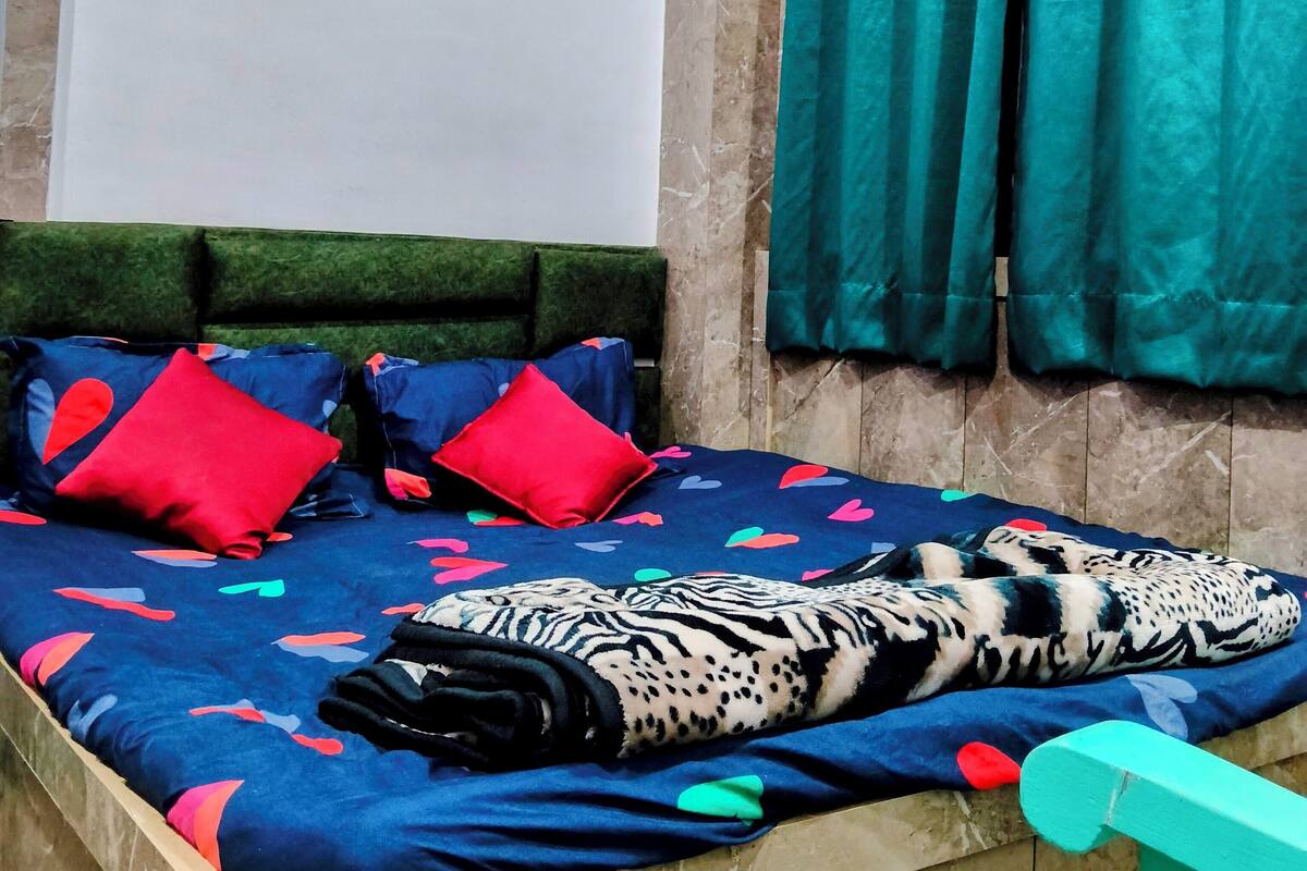A bedroom with a bed, pillows, a blanket, and curtains.