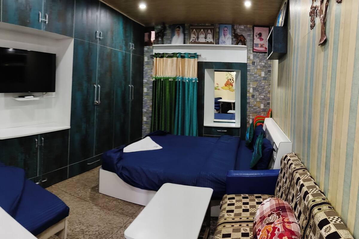A room with two blue sofas, a TV mounted on the wall, and a patterned tile backsplash.