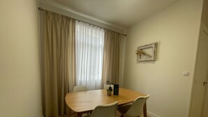 A dining area with a wooden table and four chairs, a potted plant, and a framed picture on the wall. - Airtegal Black Sands (Cedeira)